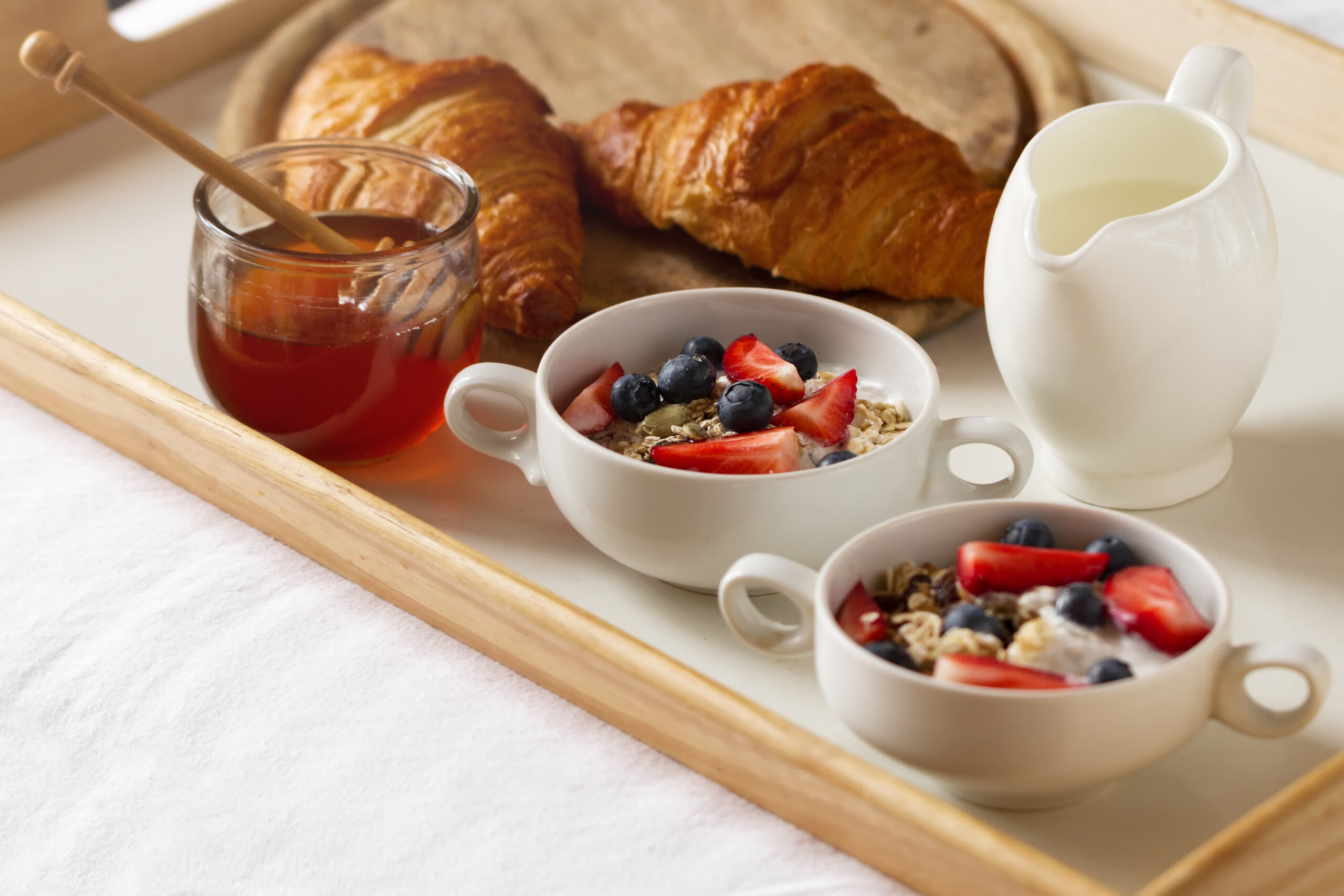 Tasty colorful Breakfast with Oatmeal, Yogurt, Strawberry, Blueberry, Honey and Milk on White Background. Breakfast in Bed. Copy Space. Top View.